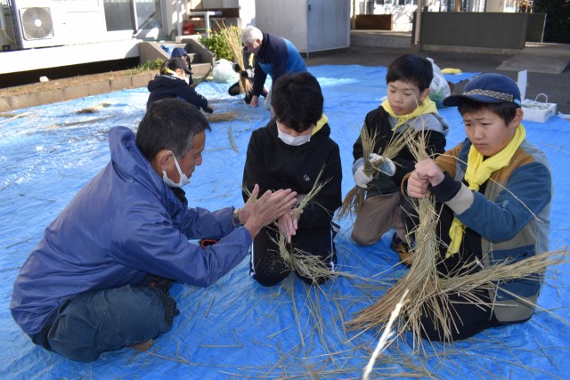 石井さん（左）の手ほどきを受けながらお飾り作りに挑戦する子どもたち＝東伊豆町の熱川小
