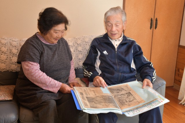 当時の新聞切り抜きを見つめ地震について語る洋子さん（左）と作之さん＝南伊豆町中木の自宅