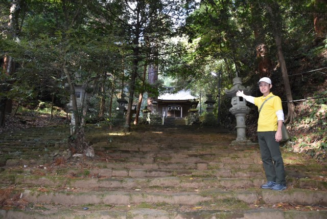 森の中に建つ八幡宮来宮神社を紹介する山崎さん＝伊東市八幡野