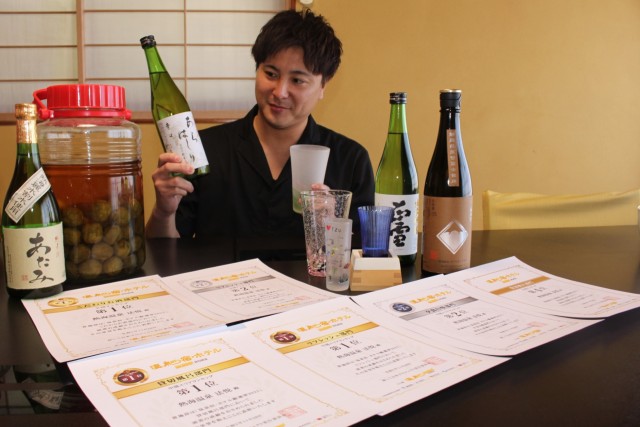 賞状とこだわりの酒やグラスを手にする村田さん＝熱海市西山町