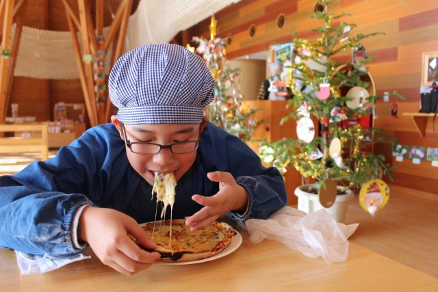 自分で作った焼きたてのピザを頬張る子ども＝熱海市伊豆山の姫の沢公園（１２月２４日）