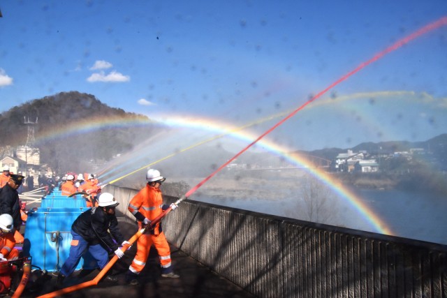 ３年ぶりに狩野川で一斉放水する団員。七色の水柱の間に虹が架かった＝伊豆市役所から放水