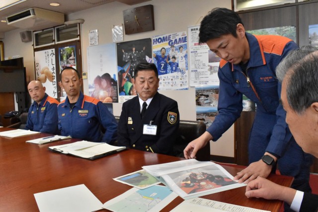 被災地で撮影した写真を見せながら活動について説明する鈴木さん＝三島市役所