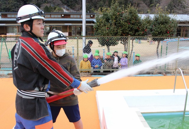 消防団員と一緒に放水体験する児童＝伊豆市の修善寺小学校