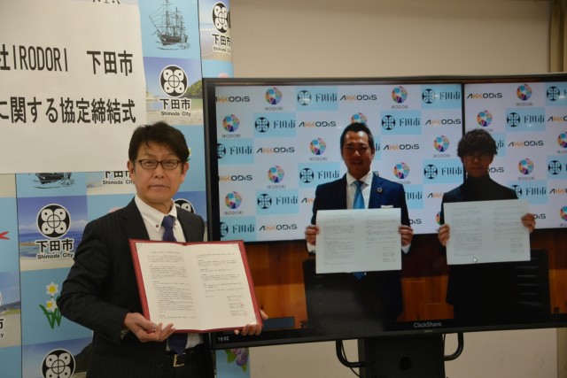 協定書を披露する松木市長（左）とオンラインで結んだ東京会場の２社の社長＝下田市役所