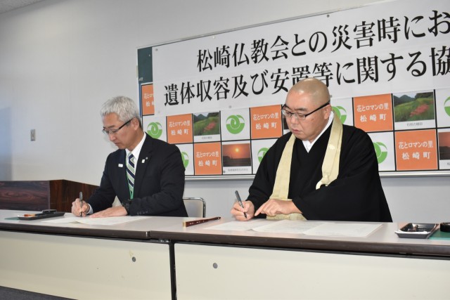 協定書に署名する堤会長（右）と深沢町長＝松崎町の環境改善センター