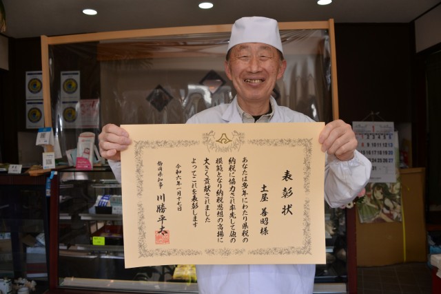 県知事からの表彰状を手に笑顔を見せる土屋さん＝下田市武ガ浜