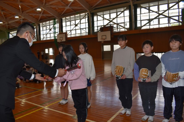児童代表にバットを手渡す滝沢会長（左）＝東伊豆町の熱川小