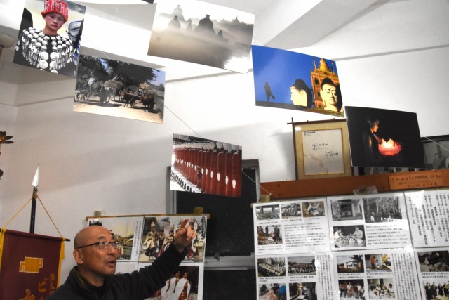 ミャンマーの写真や資料の常設展示を説明する写真家川口さん＝伊豆市八木沢の妙蔵寺パゴダ内資料館