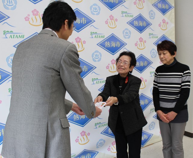 斉藤市長（左）に義援金を手渡す滝野さん（右から２人目）＝熱海市役所