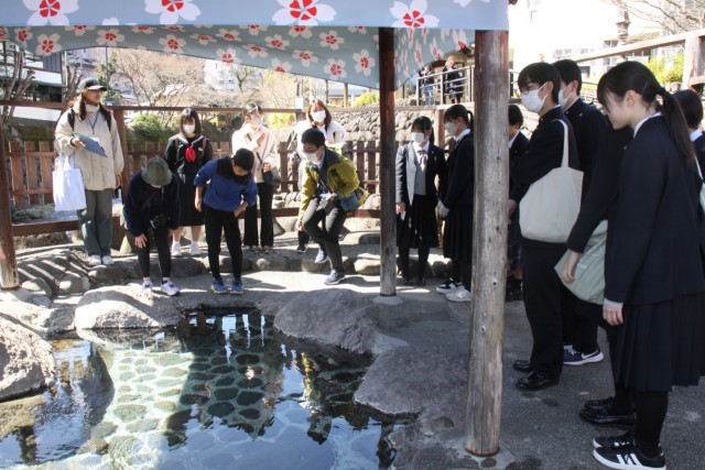 静岡大の学生（左）の説明を聞きながら「独鈷の湯」を見学する参加者＝伊豆市修善寺