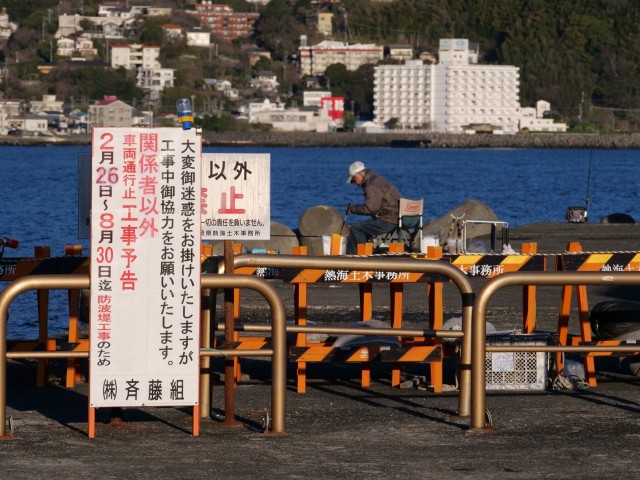 バリケードや立ち入り禁止看板の奥で釣りにいそしむ人々＝伊東市新井の外防波堤