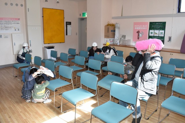 避難訓練で頭を守る参加者ら＝松崎町の生涯学習センター（１０日）