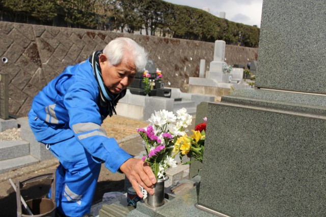 墓に花を添える墓参者＝熱海市伊豆山の熱海日金山霊園