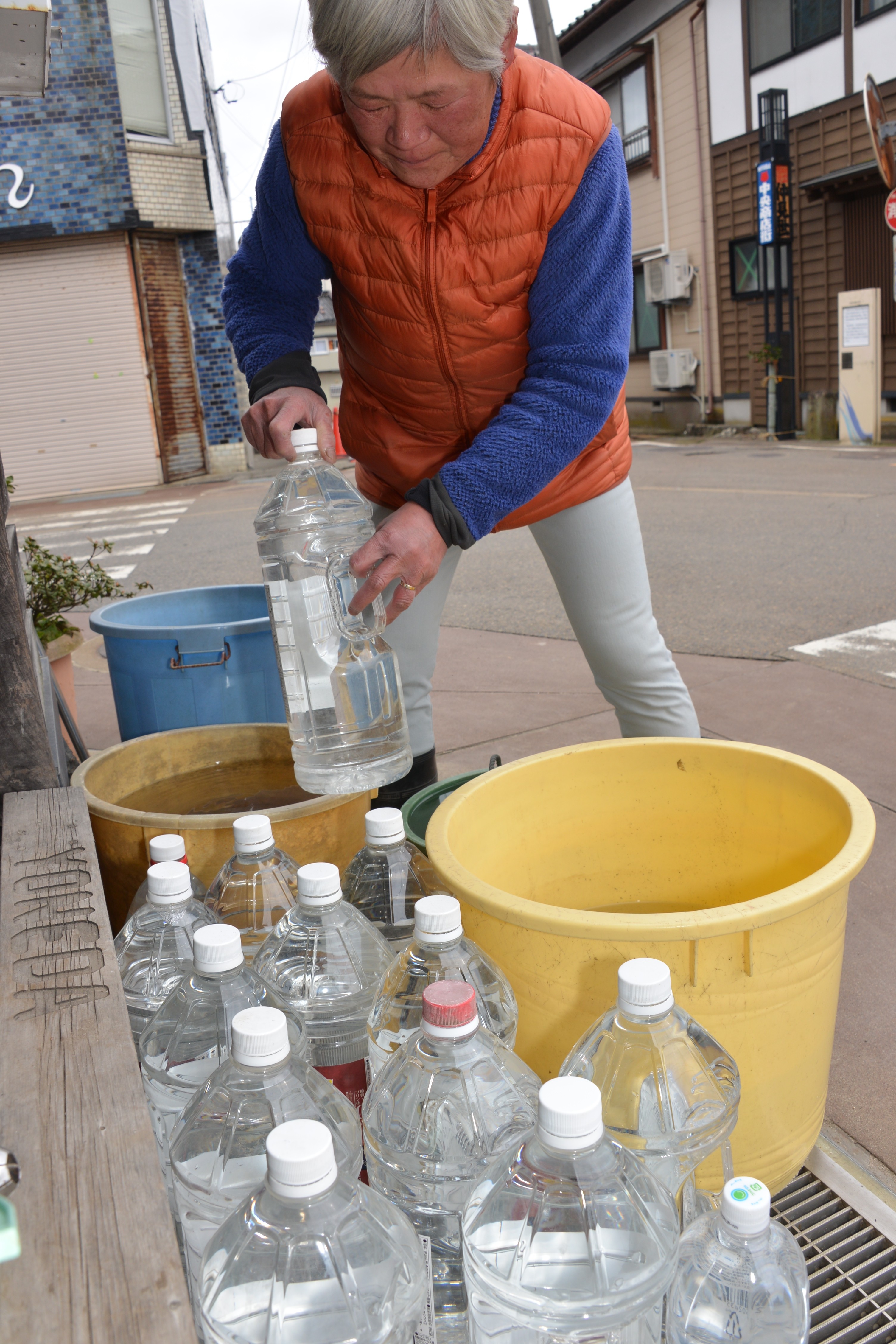 給水所からくんできたペットボトルの水を自宅に運び入れる米田さん。長引く断水で生活再建の一歩が踏み出せないと語った＝石川県珠洲市飯田町