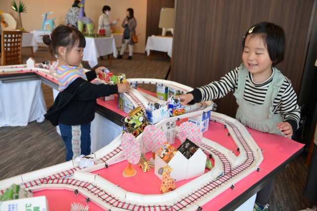 広井さんが作った紙の機関車のおもちゃで遊ぶ子どもたち＝下田市五丁目の下田東急ホテル