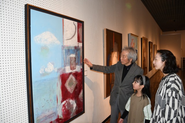 富士山を描いた新作「アトリエの一隅」を紹介する酒井さん（左）＝伊東市十足の池田２０世紀美術館