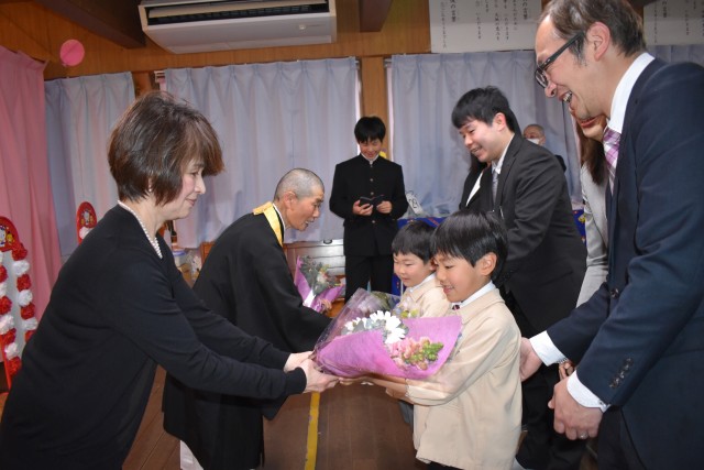 加藤園長（左から２人目）らに花束を贈る卒園児＝東伊豆町稲取の三宝保育園