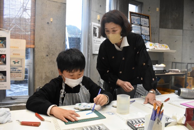 筆や鏝を使って鏝絵を描く服部さん（左）＝松崎町の「伊豆の長八美術館」