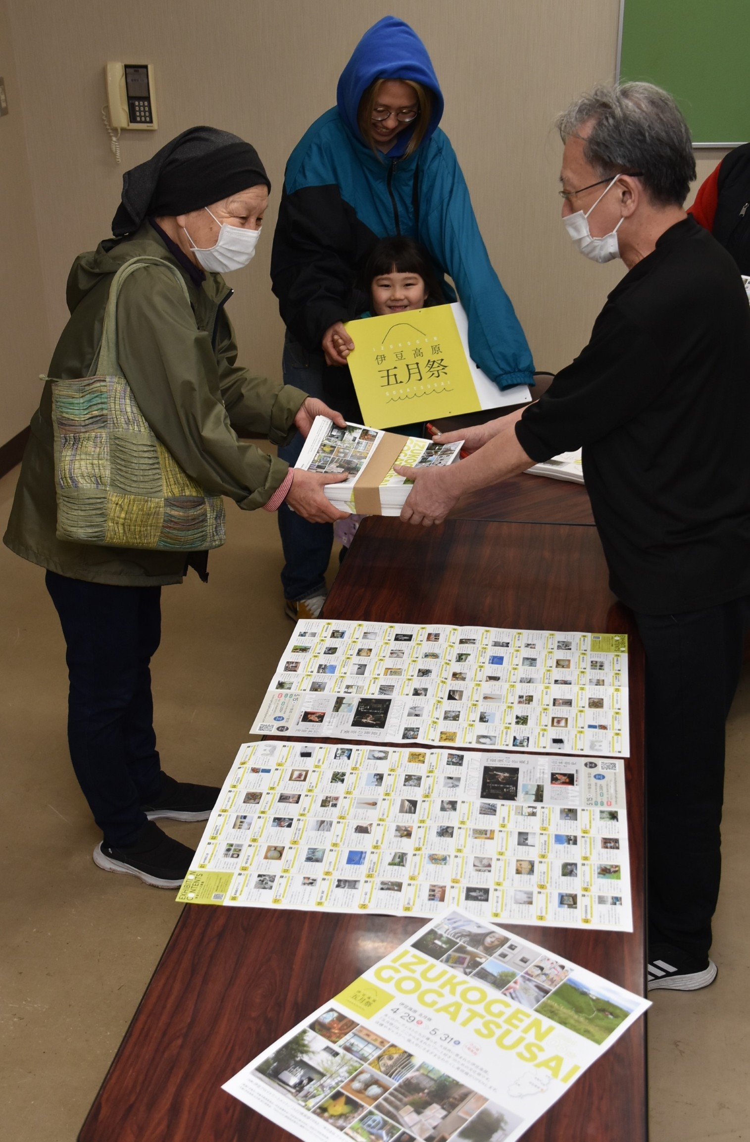 参加者にガイドブックを手渡す実行委の半左実代表（右）＝伊東市の八幡野コミュニティセンター