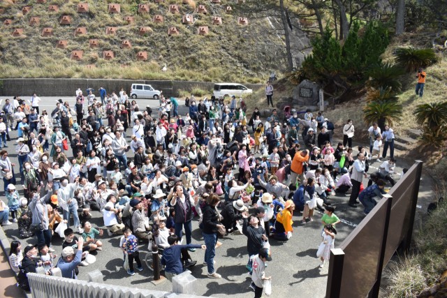 餅まきで盛り上がる来場者たち＝西伊豆町宇久須の黄金崎公園