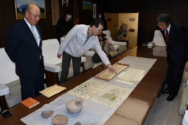 矢田さん（左）が寄贈した歴史資料の説明を受ける山下市長＝伊豆の国市役所